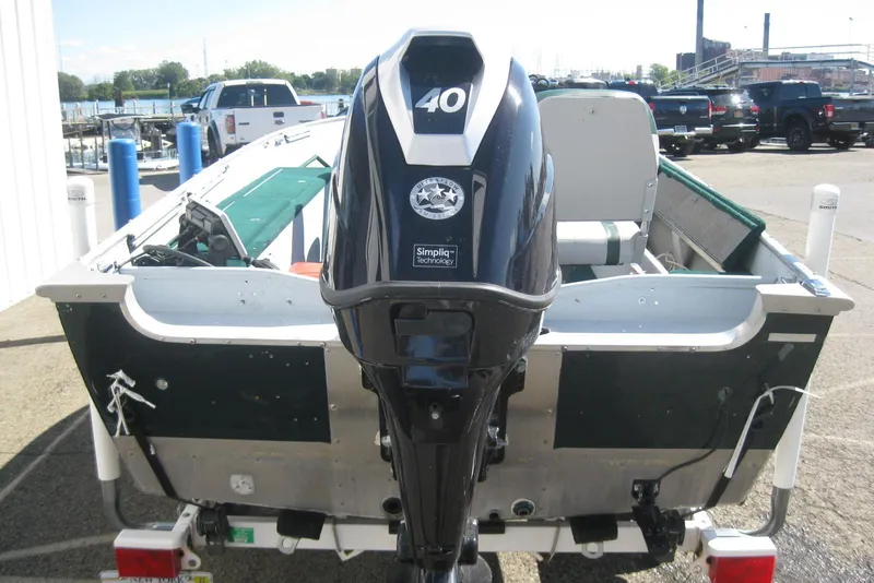 Slide: The Image of 1999 Lund 1440-V Rebel Tiller boat with 40 HP outboard motor, parked at marina. - 6