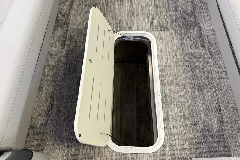 Slide: The Image of 2026 Bentley Pontoons Elite 253 Swingback storage compartment with open hatch on textured flooring. - 12