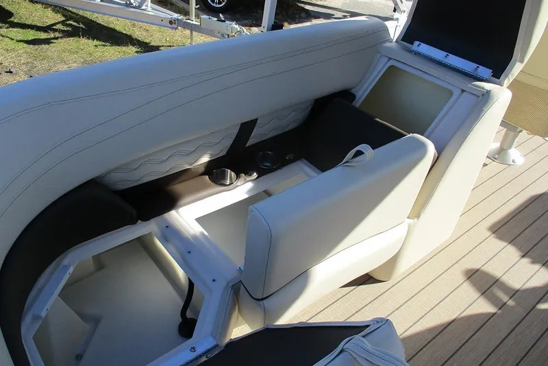 Slide: The Image of 2026 SunCatcher Fusion 324RC boat interior with open storage compartments and cup holders. - 22