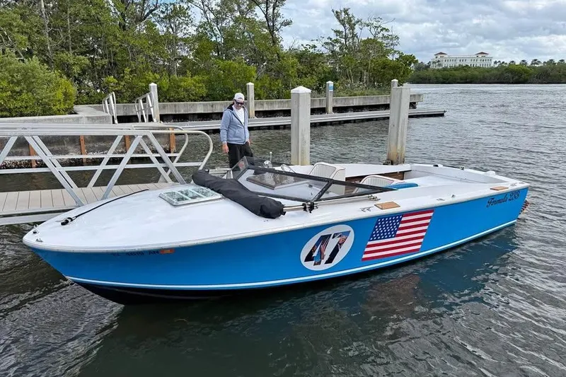 The Image of 1967 Formula 233 boat docked, featuring American flag and number 47, with person standing nearby. - 1