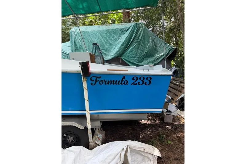 Slide: The Image of 1967 Formula 233 boat with blue hull, parked under a green tarp. - 4