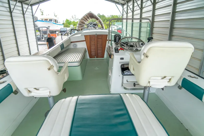 Slide: The Image of 1976 Aquasport 24 Launch boat interior with white and teal seating under a metal canopy. - 18