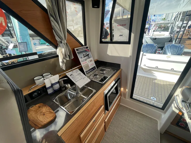 Slide: The Image of Interior of 2023 Cutwater C-288 boat featuring a compact kitchen with sink, stove, and microwave. - 27