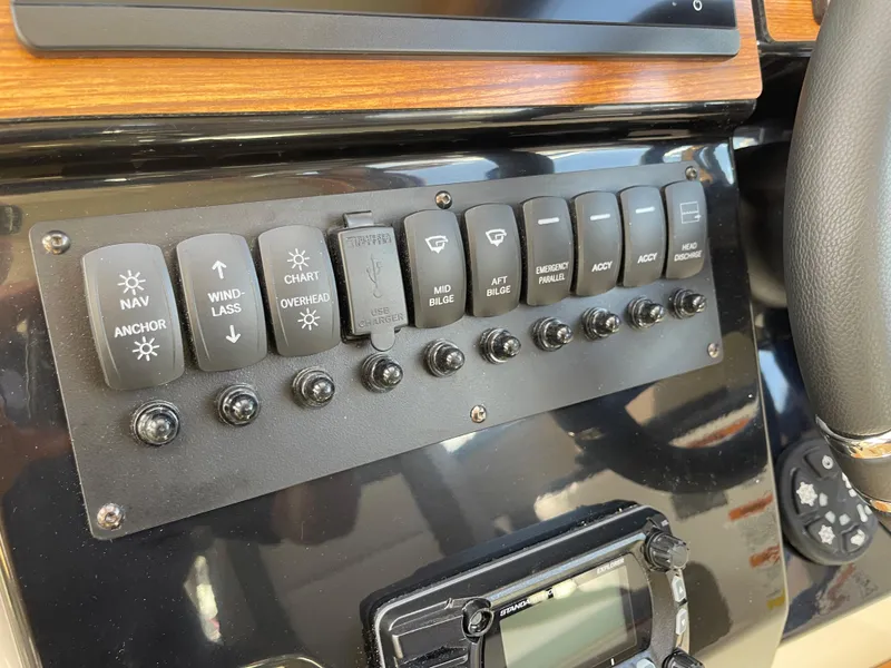 Slide: The Image of Control panel of a 2023 Cutwater C-288 boat with various switches and buttons. - 33