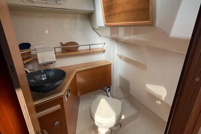 Slide: The Image of 2023 Cutwater C-288 boat bathroom with modern sink, toilet, and wooden cabinetry. - 49