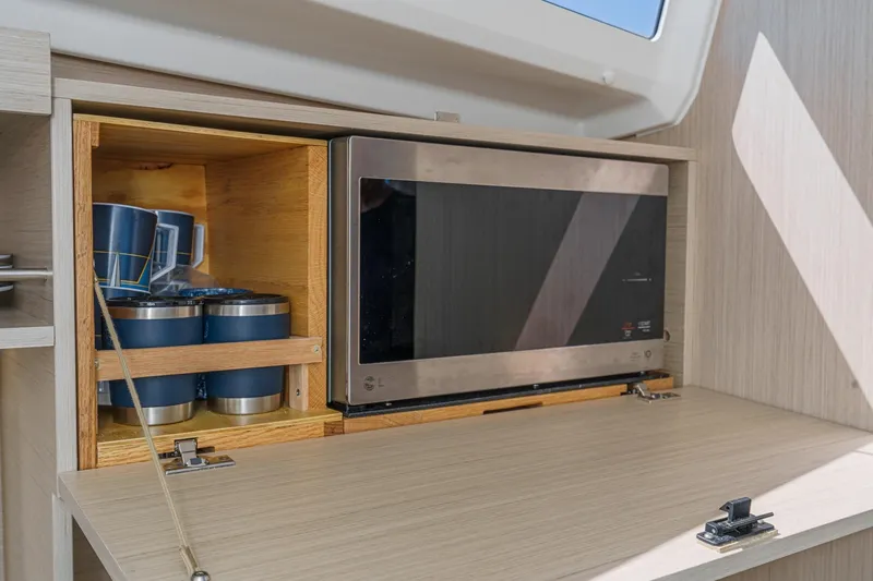 Slide: The Image of Modern kitchen setup in 2025 Beneteau Oceanis 37.1 yacht with microwave and storage. - 15