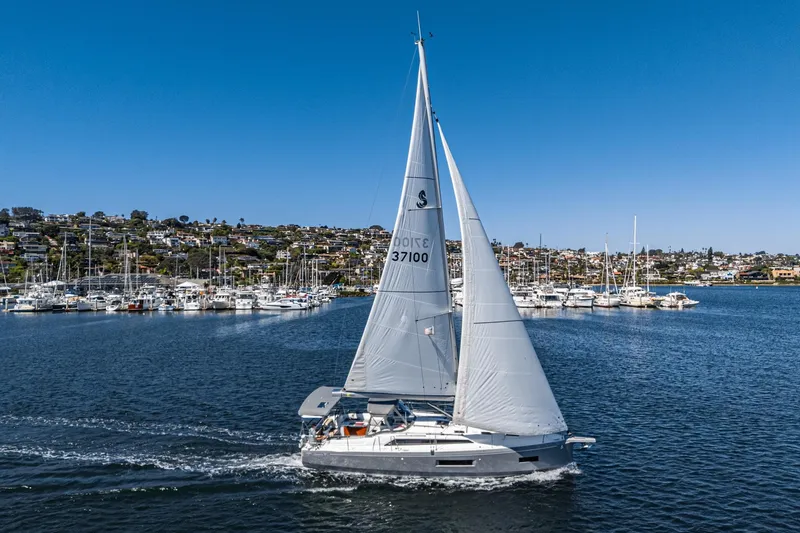 Slide: The Image of 2025 Beneteau Oceanis 37.1 sailing in a scenic harbor with clear blue skies. - 48