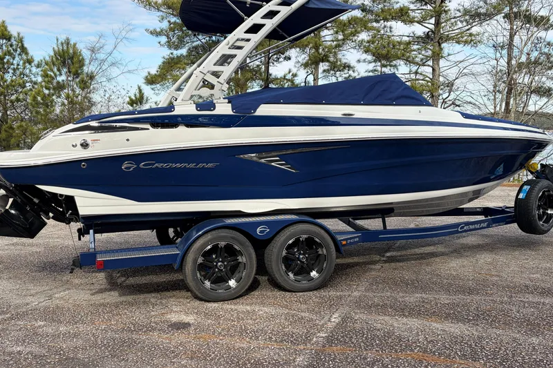Slide: The Image of 2026 Crownline 240 SS boat on trailer, blue and white design, parked outdoors. - 4