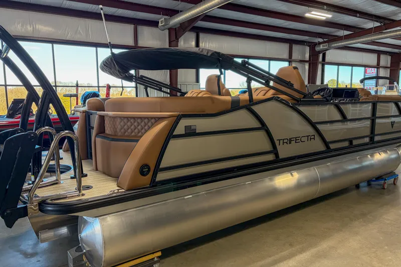 Slide: The Image of 2026 Trifecta 23 RF SS pontoon boat in showroom, featuring sleek design and luxurious seating. - 18