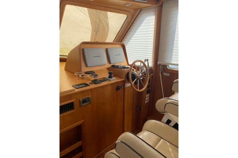 Slide: The Image of 2010 Sabre 38 Express helm with Garmin navigation, wooden steering wheel, and beige seating. - 15