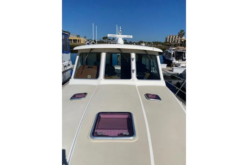 Slide: The Image of 2010 Sabre 40 Sedan boat docked, featuring a beige deck and multiple windows. - 68