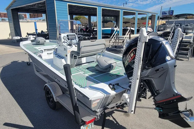 Slide: The Image of 2024 Xpress H22B Bay boat with outboard motor, parked near a blue building. - 4