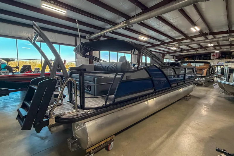 The Image of 2026 Trifecta 25 UL SS pontoon boat displayed in a spacious indoor showroom. - 1