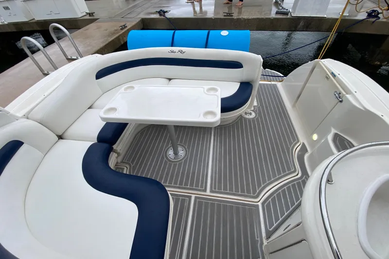Slide: The Image of 2004 Sea Ray 340 Sundancer cockpit with white and blue seating, table, and gray flooring. - 15