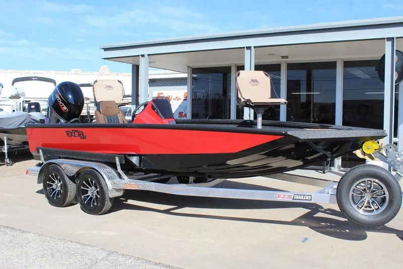 The Image of 2026 Excel EX 183 boat in red and black on a trailer, parked outside a building. - 1