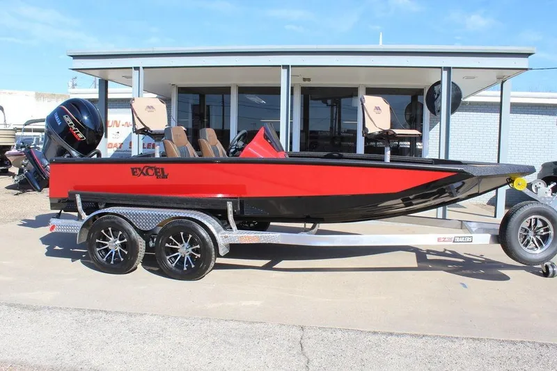 Slide: The Image of 2026 Excel EX 183 boat in red and black on a trailer, parked outside a building. - 4