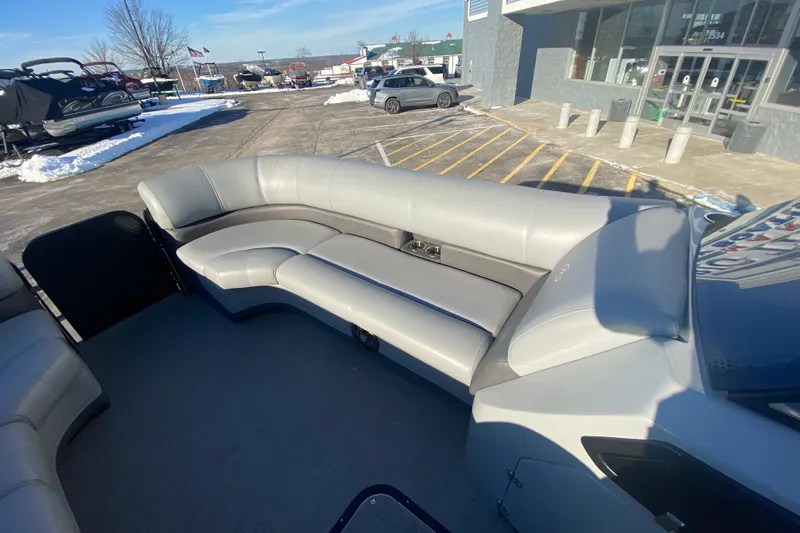 Slide: The Image of 2022 Manitou 25 OASIS RF SHP pontoon boat interior with gray seating, parked outdoors. - 12