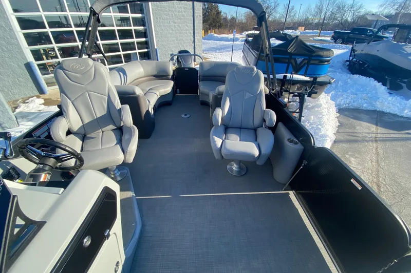 Slide: The Image of 2022 Manitou 25 OASIS RF SHP pontoon boat interior with plush seating and steering console. - 14
