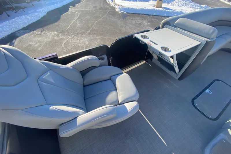 Slide: The Image of 2022 Manitou 25 OASIS RF SHP boat interior with gray seating and foldable table. - 25