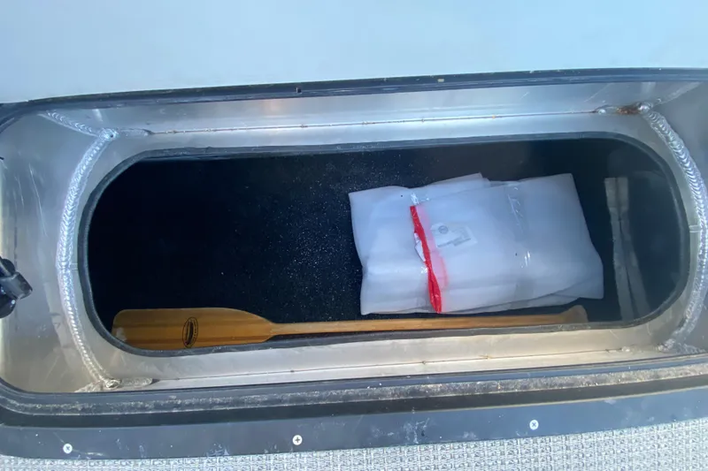 Slide: The Image of Storage compartment in 2022 Manitou 25 OASIS RF SHP with paddle and wrapped item. - 28