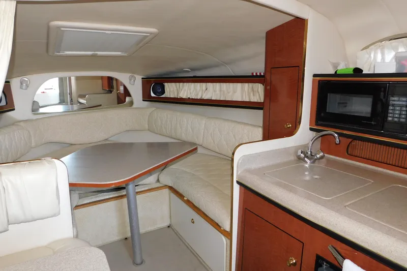 Slide: The Image of Interior of 2001 Sea Ray Sundancer 280, featuring a cozy dining area and kitchenette. - 16