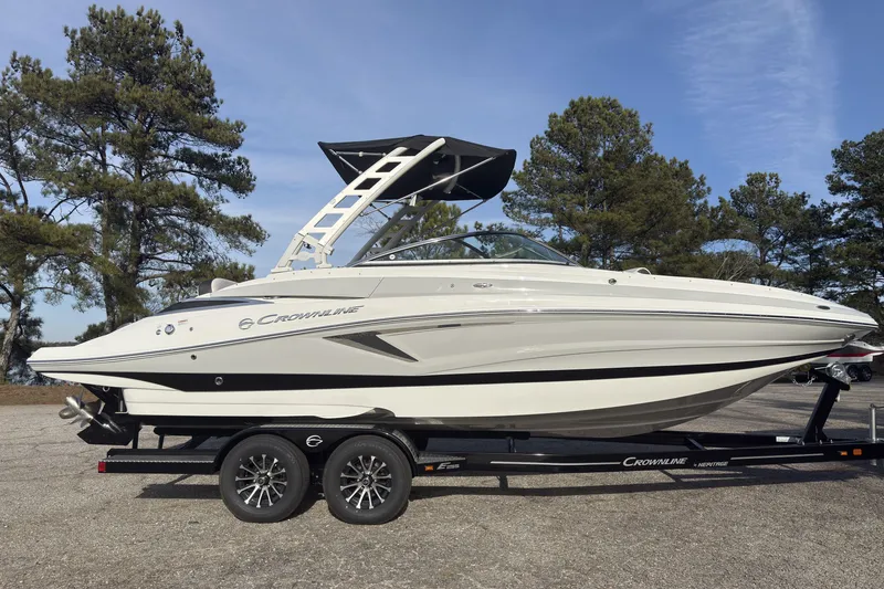 The Image of 2026 Crownline Eclipse E255 boat on trailer, parked outdoors with trees in background. - 1