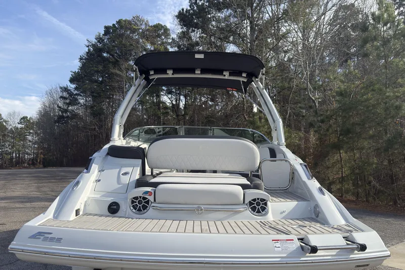 Slide: The Image of 2026 Crownline Eclipse E255 boat with sleek design, parked outdoors near trees. - 4