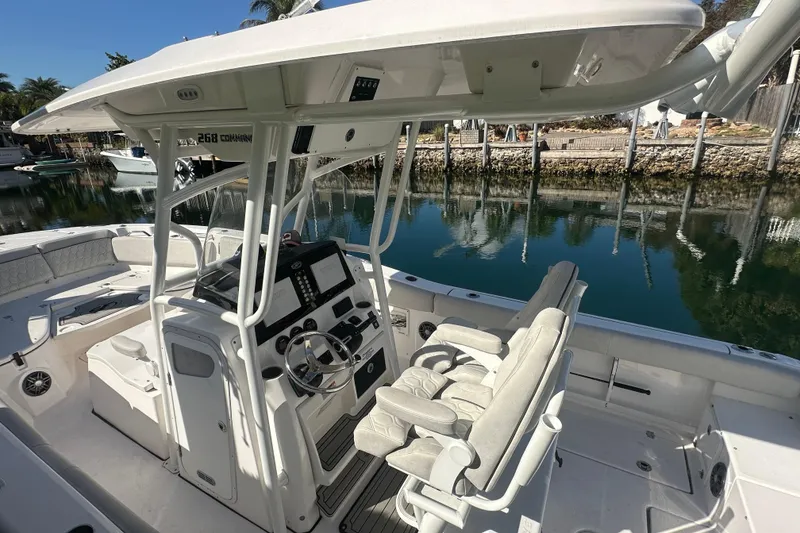 Slide: The Image of 2023 Sea Fox 268 Commander boat interior with helm and seating, docked by calm water. - 9