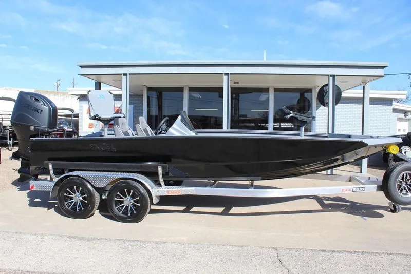 Slide: The Image of 2026 Excel EX 203 boat on trailer, parked outside a building under clear blue sky. - 2