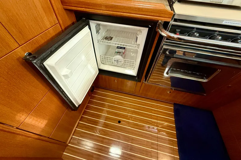 Slide: The Image of 2007 Hunter 44 Deck Salon interior with open fridge and stove, showcasing wood finish. - 26