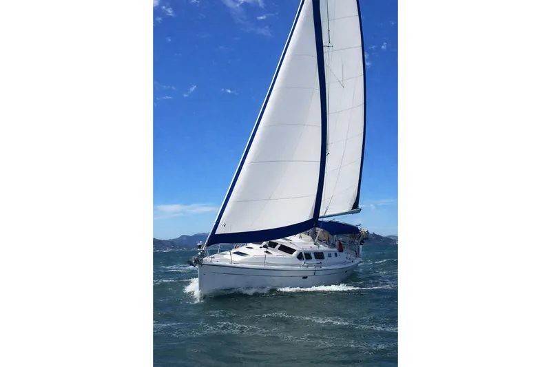 Slide: The Image of 2007 Hunter 44 Deck Salon sailboat navigating open waters under clear blue skies. - 4