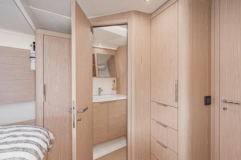 Slide: The Image of Interior of 2022 Beneteau Oceanis Yacht 54, featuring modern wood cabinetry and bathroom. - 16