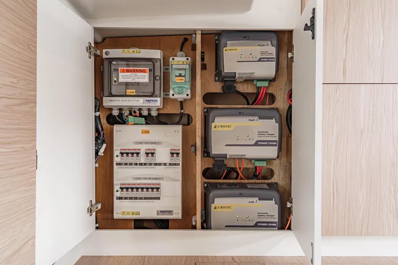 Slide: The Image of Electrical panel inside 2022 Beneteau Oceanis Yacht 54, featuring battery chargers and circuit breakers. - 27