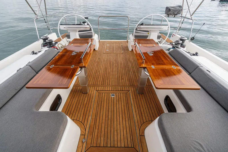Slide: The Image of Luxurious 2022 Beneteau Oceanis Yacht 54 deck with elegant wooden tables and seating. - 68