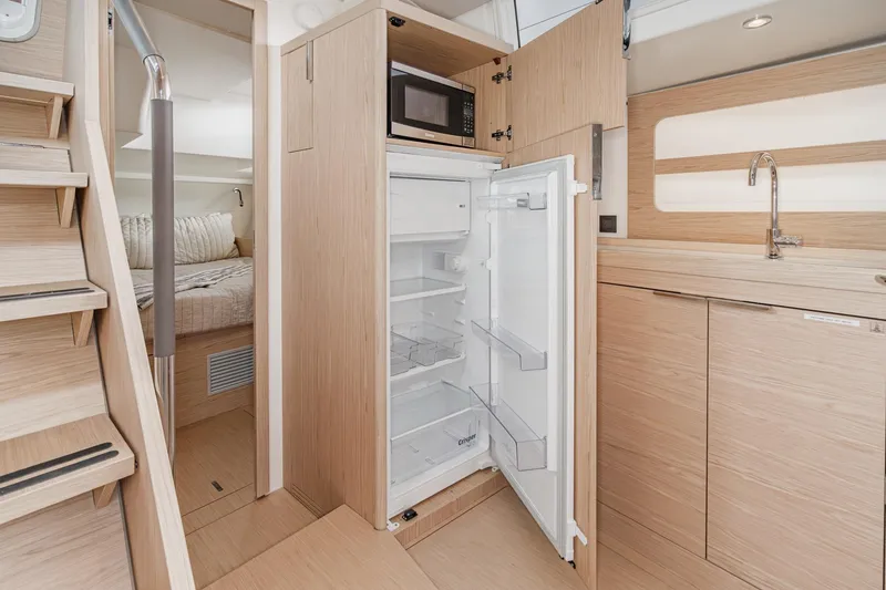 Slide: The Image of Interior of 2022 Beneteau Oceanis Yacht 54, featuring modern kitchen with open fridge. - 7