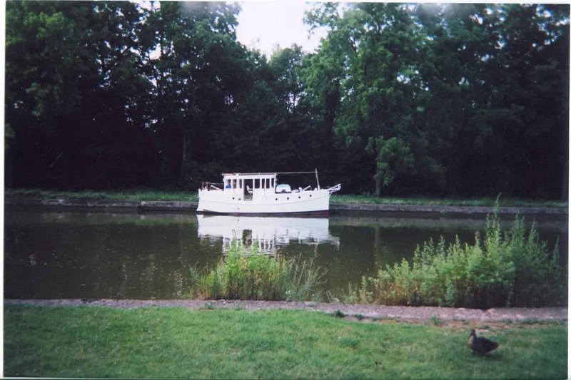 Slide: The Image of Custom 2005 sail-assisted trawler on a serene river, surrounded by lush greenery. - 1