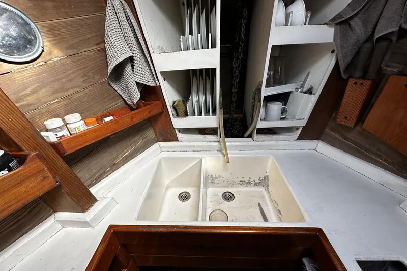 Slide: The Image of Compact kitchen area in a 2005 custom sail-assisted trawler, featuring a sink and storage shelves. - 10