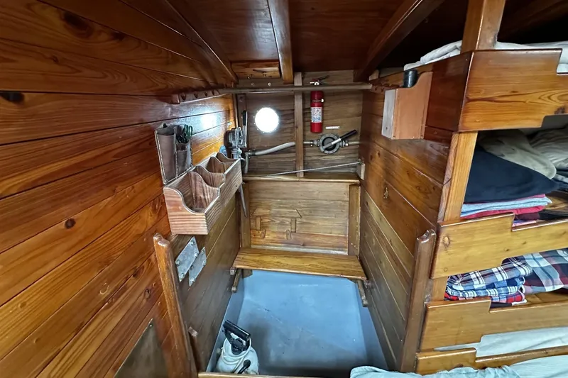 Slide: The Image of Wood-paneled cabin interior of 2005 Custom Sail-Assisted Trawler with storage and porthole. - 22