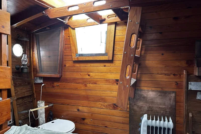 Slide: The Image of Wood-paneled interior of a 2005 custom sail-assisted trawler with porthole and heater. - 23