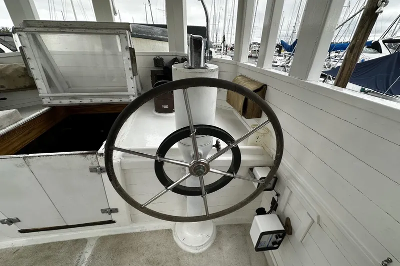 Slide: The Image of Helm of 2005 Custom Sail-Assisted Trawler with large steering wheel, docked in marina. - 27
