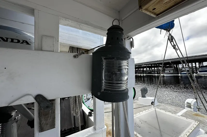 Slide: The Image of Lantern on 2005 Custom Sail-Assisted Trawler, docked near marina with bridge in background. - 32