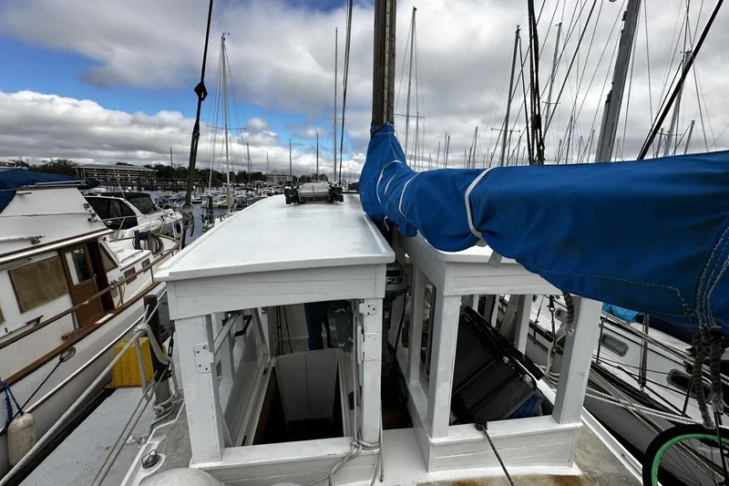 Slide: The Image of Custom 2005 sail-assisted trawler docked at marina, featuring blue sail cover and white cabin. - 35