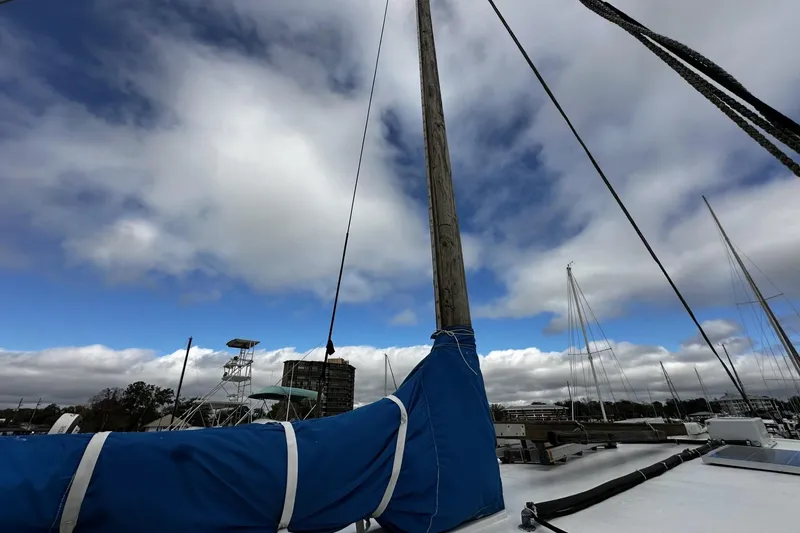 Slide: The Image of Custom 2005 sail-assisted trawler mast against a cloudy sky in a marina setting. - 36