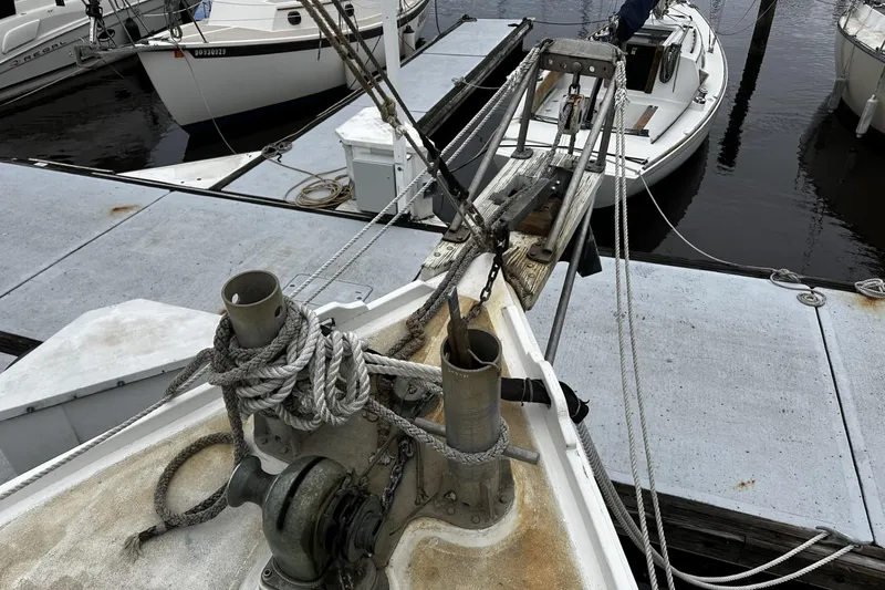 Slide: The Image of Bow of a 2005 custom sail-assisted trawler docked, featuring ropes and winch. - 43