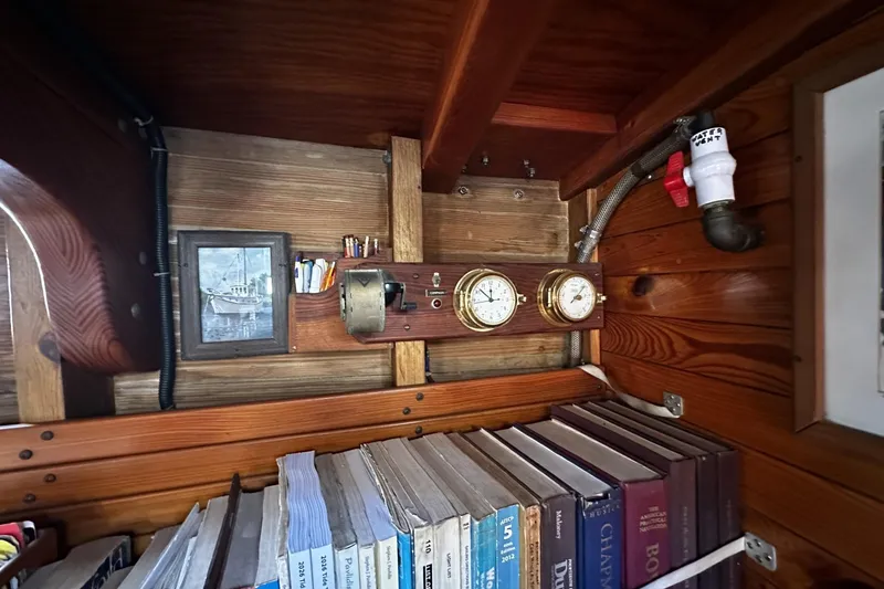 Slide: The Image of Wooden interior of a 2005 custom sail-assisted trawler with books, gauges, and nautical decor. - 56