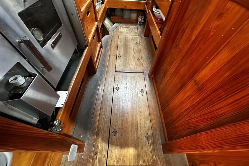 Slide: The Image of Wooden interior of a 2005 Custom Sail-Assisted Trawler, featuring a narrow galley with storage. - 58