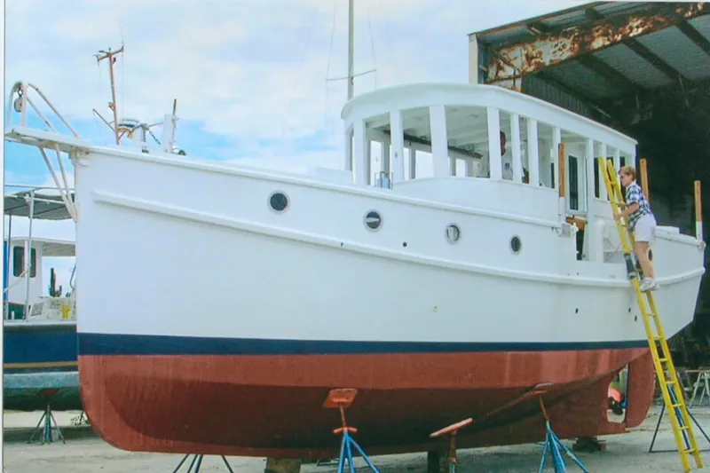 Slide: The Image of Custom 2005 sail-assisted trawler in dry dock, with person on ladder for maintenance. - 66