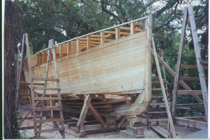 Slide: The Image of Wooden sail-assisted trawler under construction, surrounded by trees, 2005. - 68