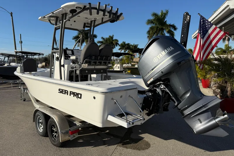 Slide: The Image of 2025 Sea Pro 230 Bay boat with Yamaha engine on trailer, American flag in background. - 10