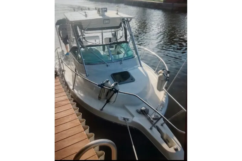 Slide: The Image of 2001 Robalo 2440 Walkaround boat docked on calm water. - 1